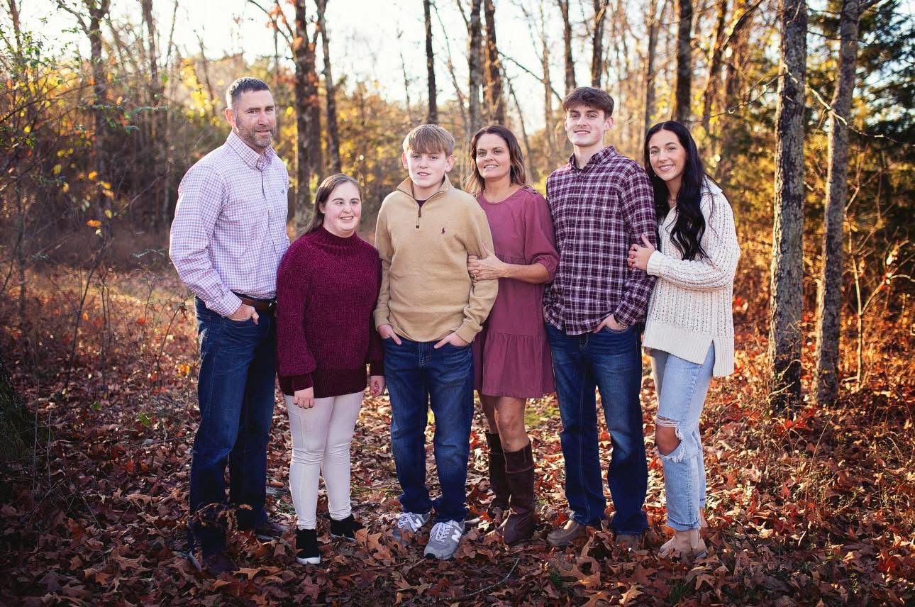 The Goodwin family together outdoors among autumn trees.